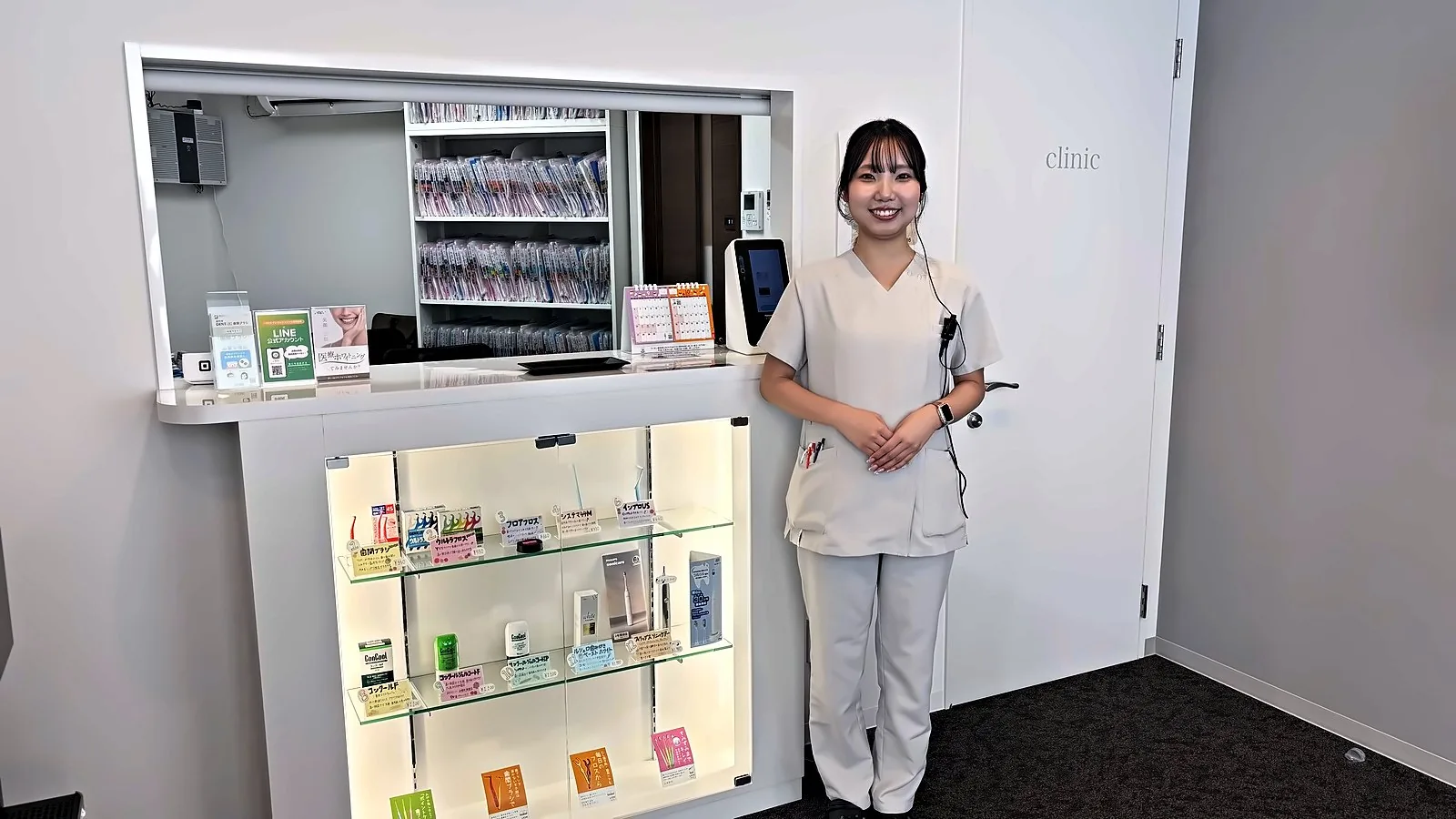 いずたにデンタルクリニック枚方本院の受付カウンターと、歯ブラシやフロスなどのケア用品を並べたショーケース